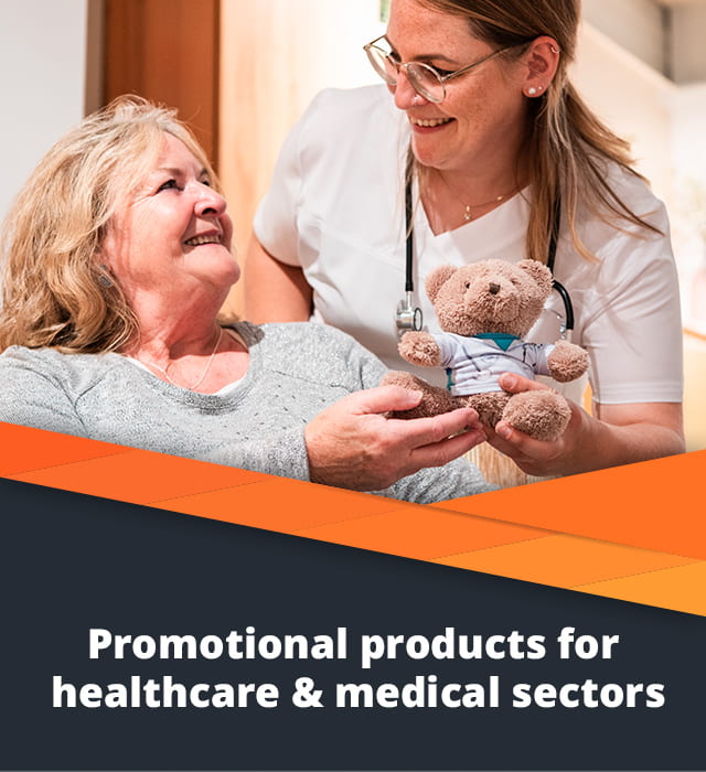 A nurse hands a teddy bear to a patient