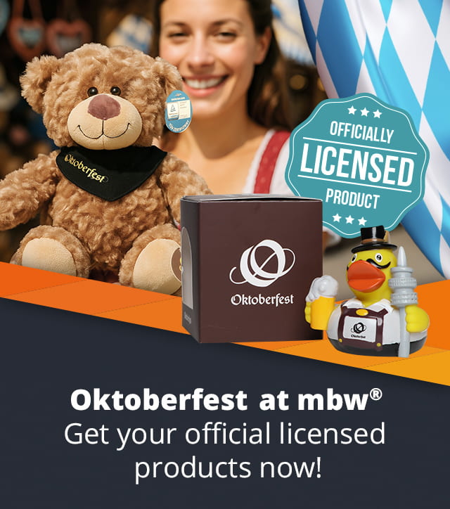 A woman in traditional Bavarian dress holds a teddy bear with an Oktoberfest scarf up to the camera.